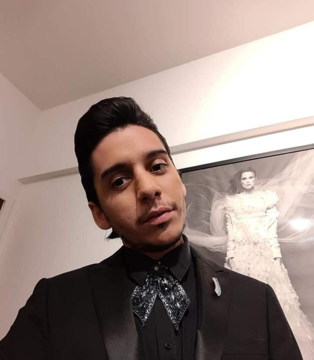 Táiguel vestido formalmente diante de uma obra de arte